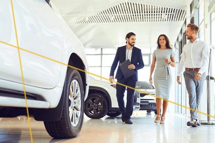 two car buyers and a dealership salesperson in an Instant Cash Offer dealership showroom