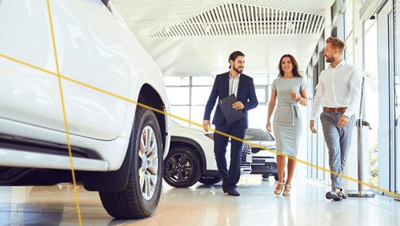 two car buyers and a dealership salesperson in an Instant Cash Offer dealership showroom