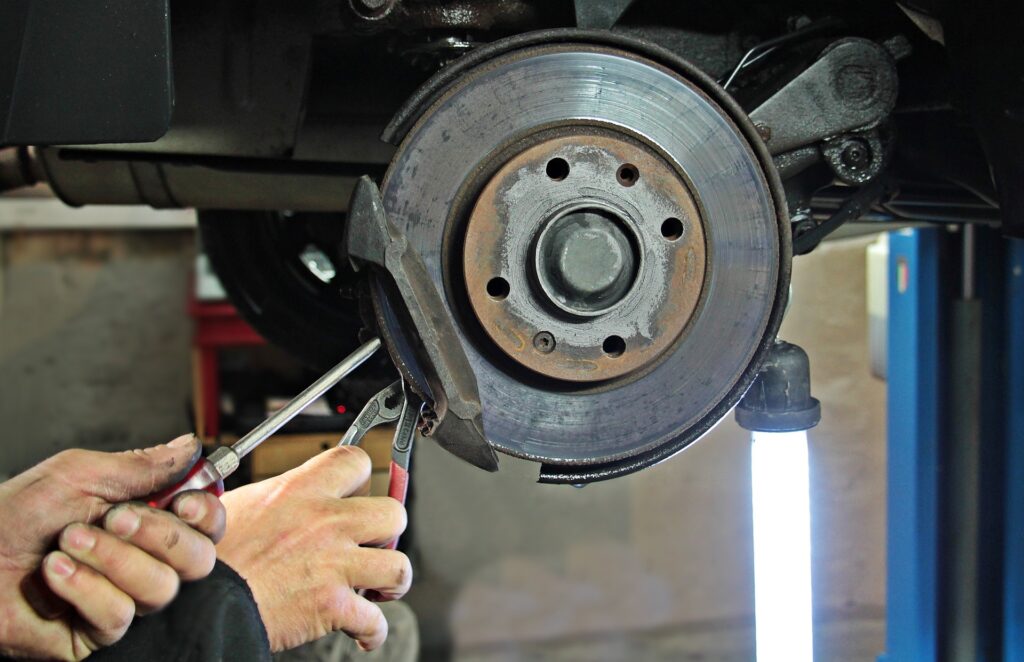 A mechanic working on a vehicle's brakes. 