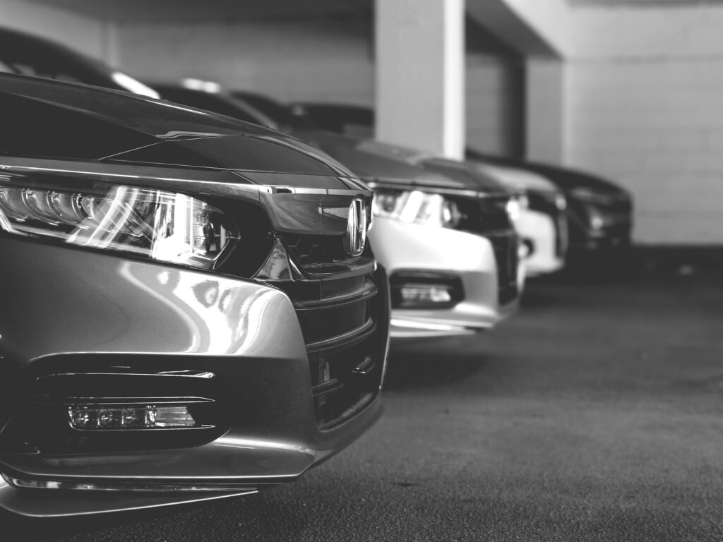 greyscale photo of new cars on the showroom floor